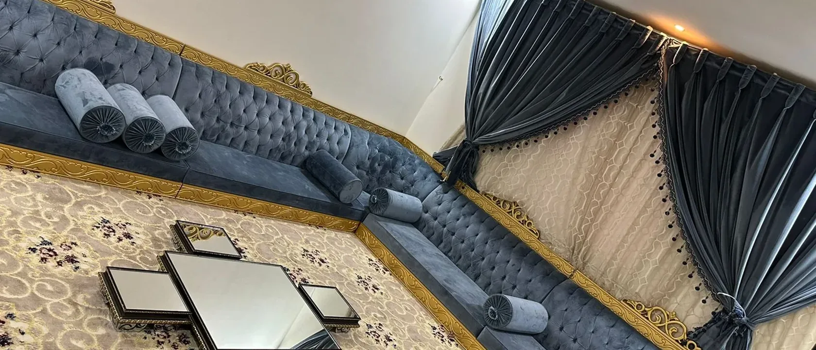 مجلس بجلسات زرقاء وستائر طويلة وسجادة مزخرفة عند اختيار أفضل شركة تنظيف بالرياض